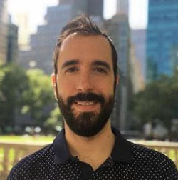 Man with beard in front of buildings